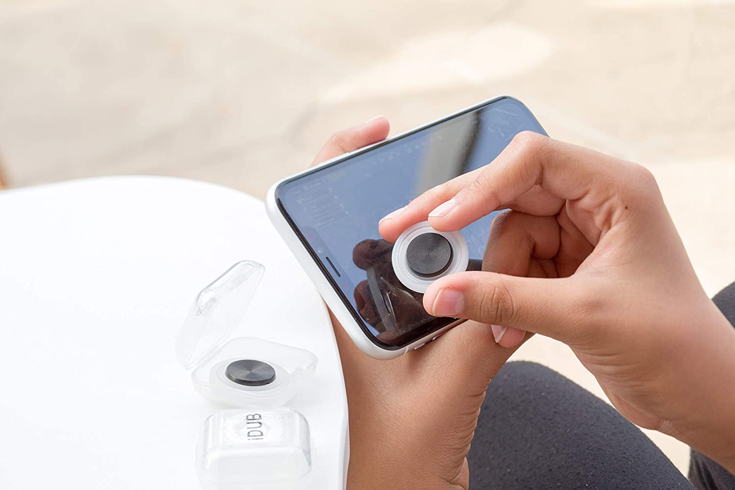 A hand gripping the iDub Mobile Gaming Joystick, which adheres to your phone's screen.