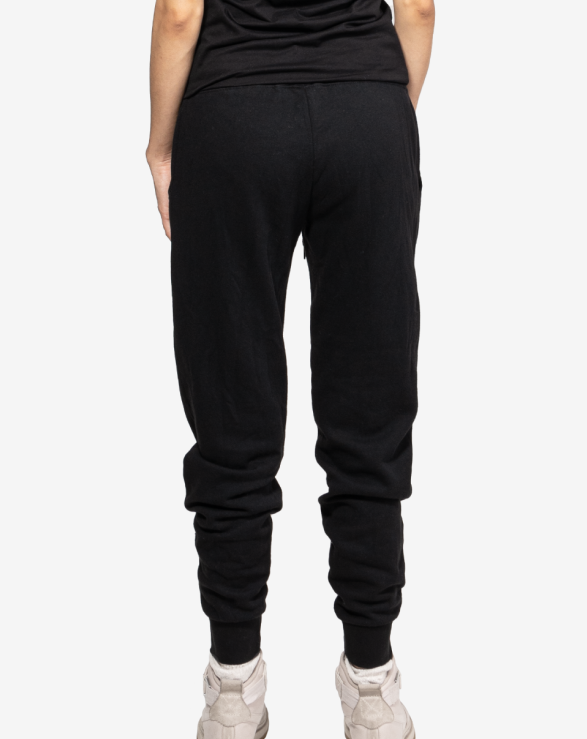 
 A back view of black joggers with a pocket on the right side on a model.
 